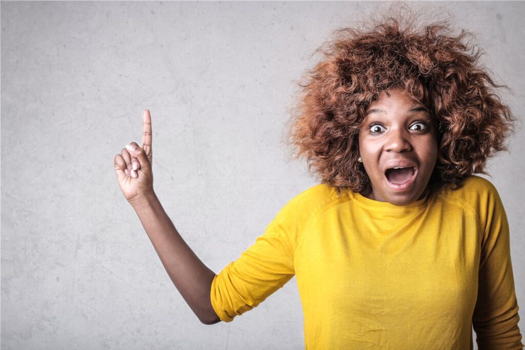 a woman in a yellow tshirt looking surprised pointing up. What is branding? Its the emotions you are trying to evoke.