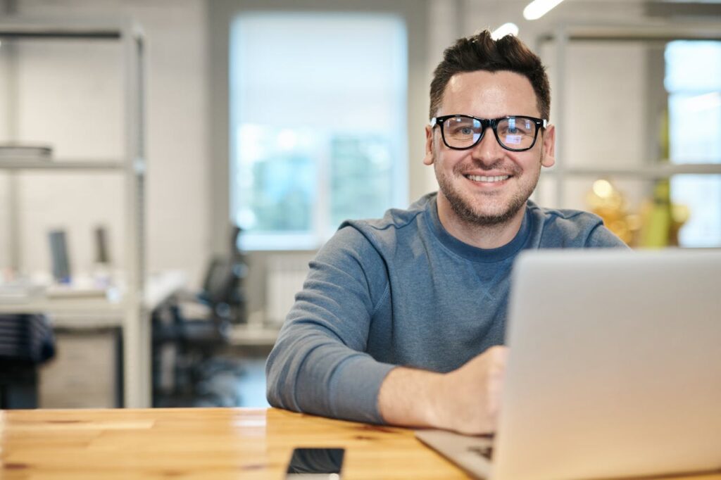 online web design courses uk. A man at a laptop wearing glasses. A very happy chap.