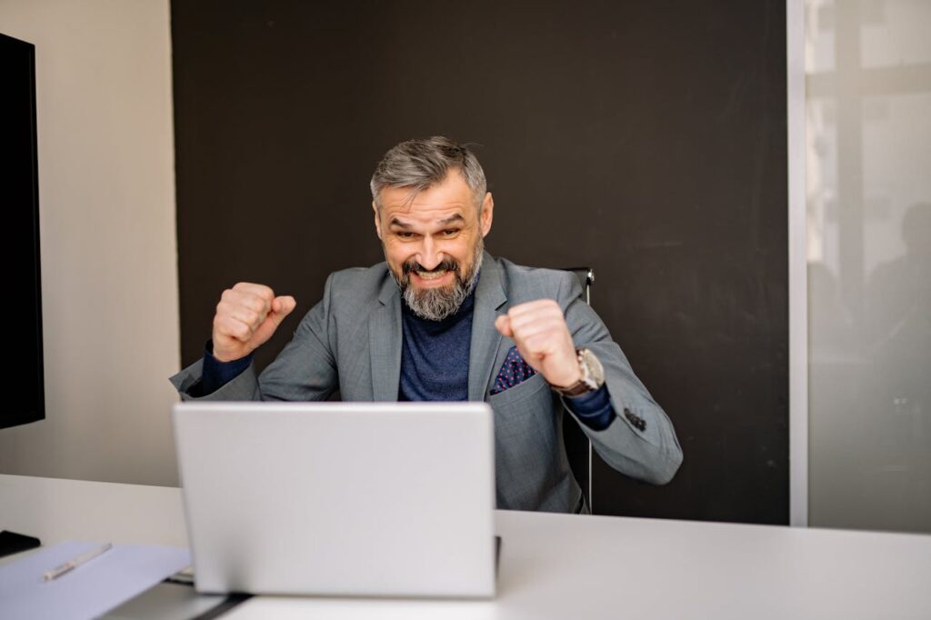where to start learning web design. When you find it you feel like this guy! A picture of a man in a suit jacket looking at a laptop punching the air with a big smile on his face. The guy has a grey beard, he looks late 40s. Seems happy to have found The Design Mentor!