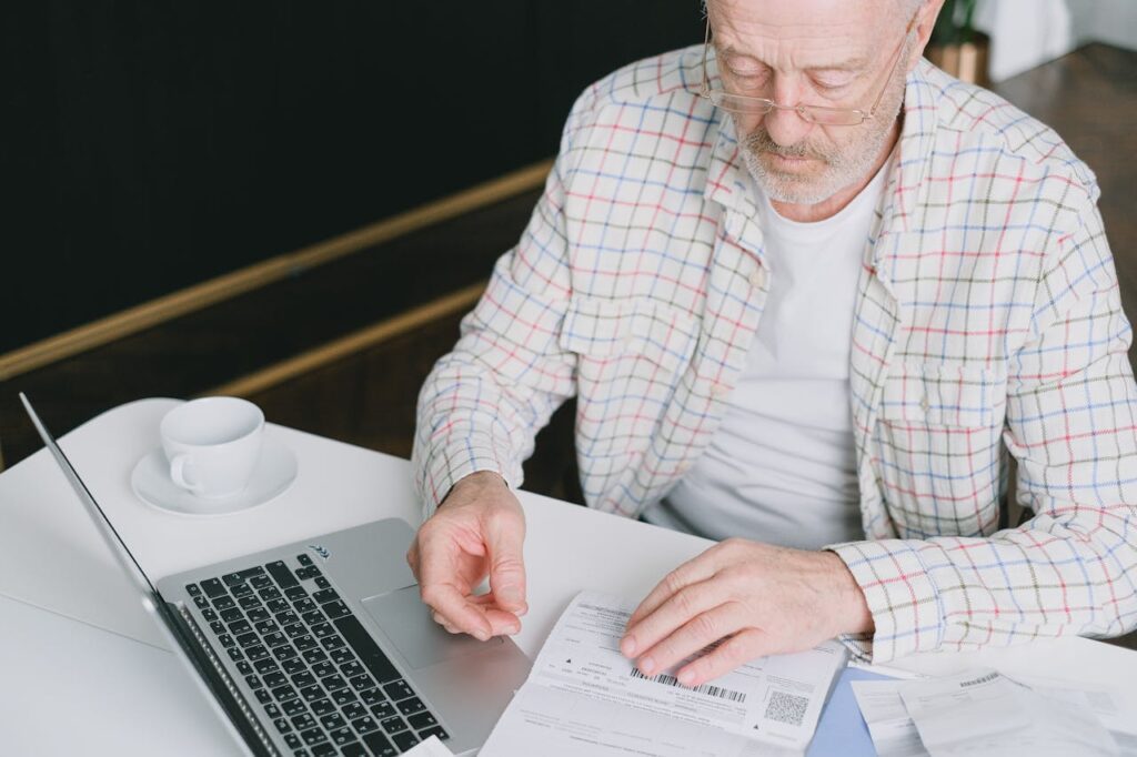 how to design a logo for beginners analyse the competition. an older man sitting at a laptop looking at his notes.