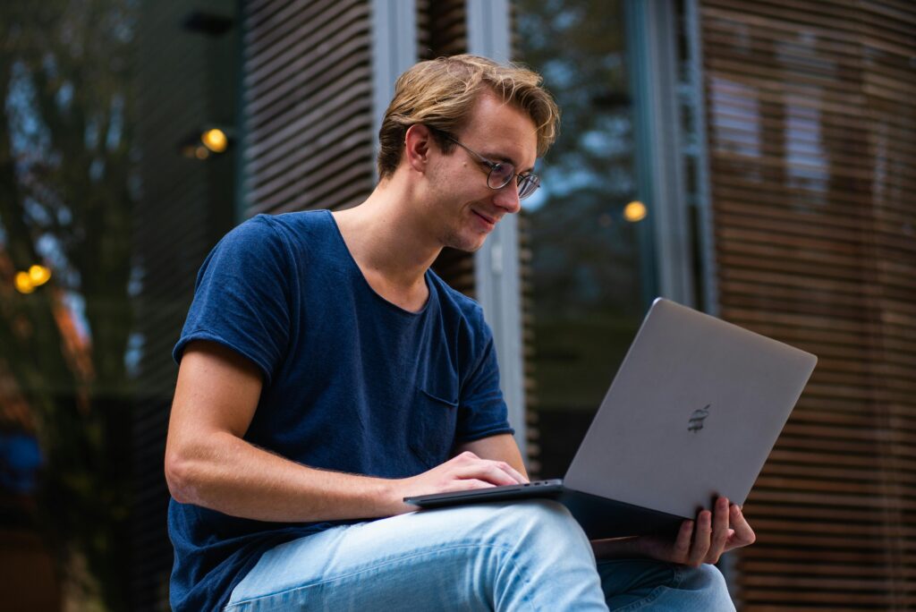 this guy is a on a laptop smilong at the screen, probably realising that The Design Mentor offers the best online web design courses around